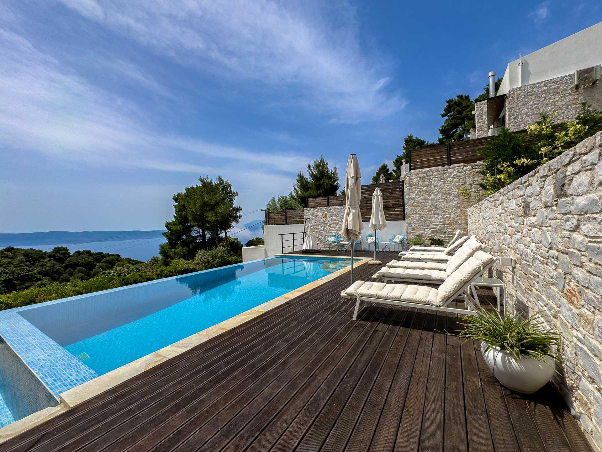 Private infinity pool at a luxury Skiathos villa surrounded by Mediterranean pine trees and natural greenery